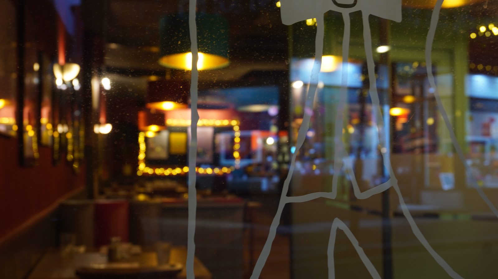 Kendricks interior at night, viewed through the window with the waiter illustration on the glass