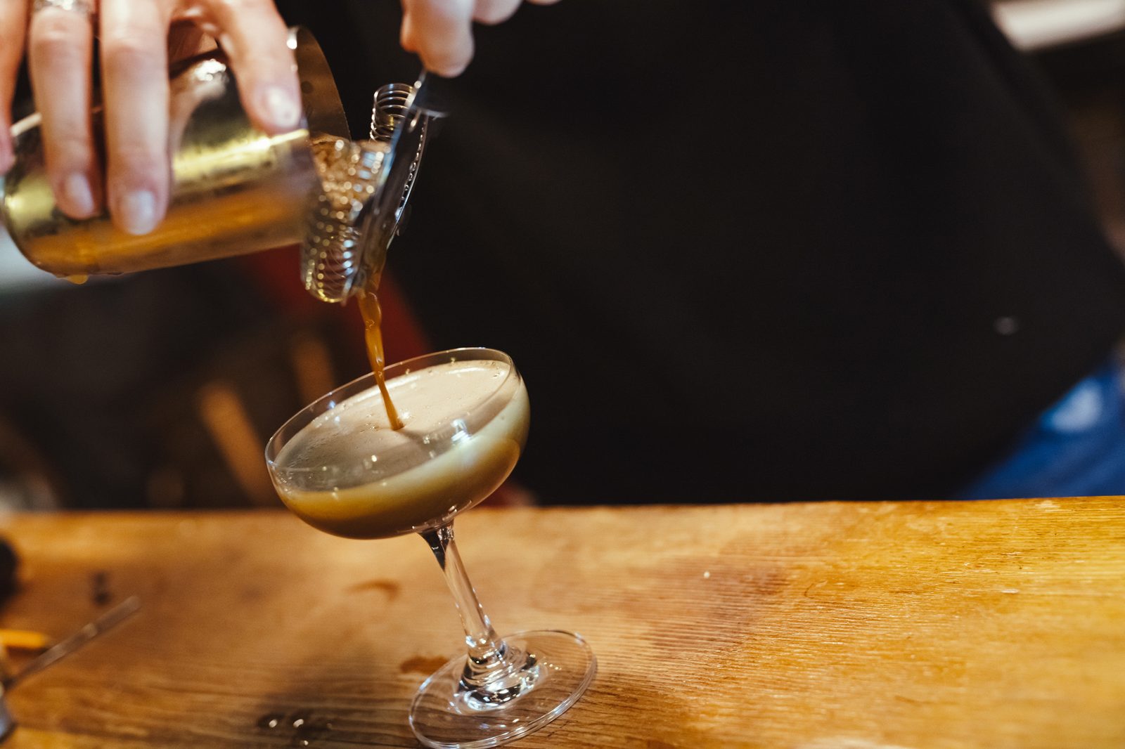 An espresso martini being poured from a shaker into a coupe glass