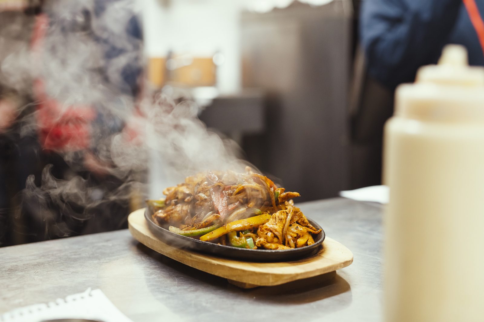 A sizzling fajita platter steaming on a wooden board